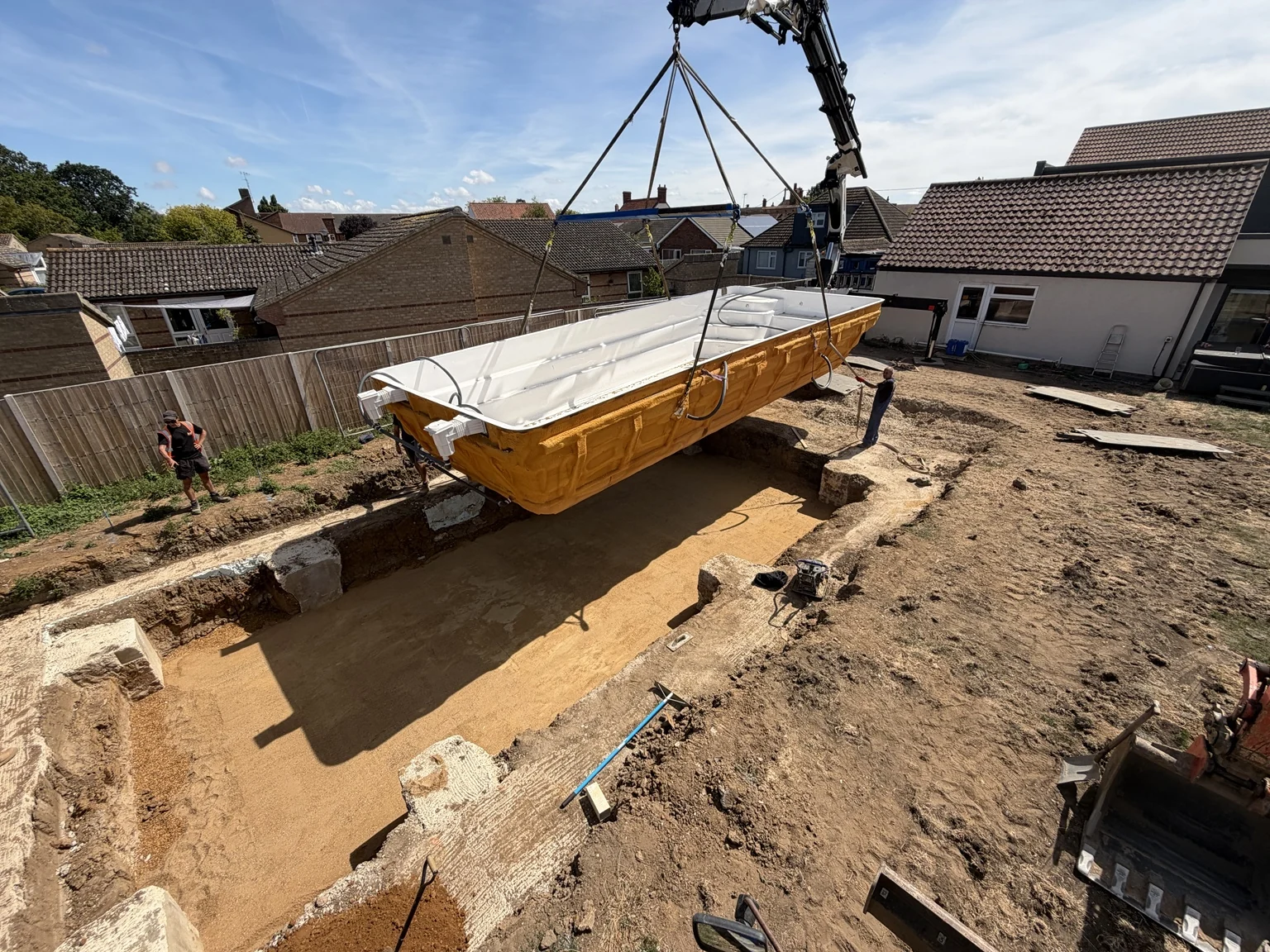 Swimming pool shell being lowered into the prepared excavation by crane